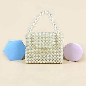Detail of handmade white pearl beaded box bag with large pearl handle and flap closure