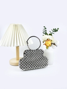 Handmade silver beaded shell clutch bag with large round metal handle on white background