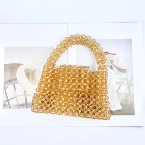 Détail d'un sac à main artisanal en perles acryliques ambrées sur un magazine