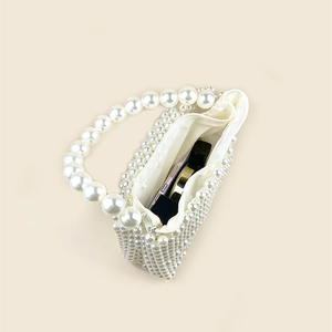 Detailed interior of a white pearl beaded box bag holding a smartphone and cosmetics