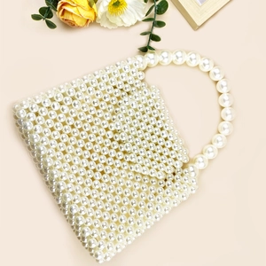 Close-up of a handmade box-shaped pearl beaded handbag with large pearl handle details