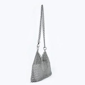 Macro detail of silver metal sequin mesh texture on a handmade woven crossbody bag
