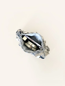 Silver sequin clutch bag showing internal storage for phone, lipstick and powder compact