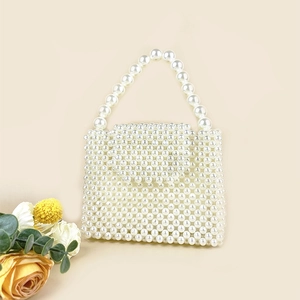Detailed close-up of handmade white pearl woven square handbag with elegant top handle