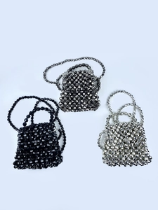 Three mini woven beaded handbags in black, gunmetal, and silver shown from a top view