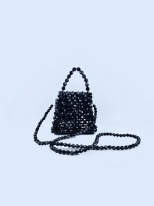 Detail of hand-woven black beaded handbag featuring faceted beads and glossy texture
