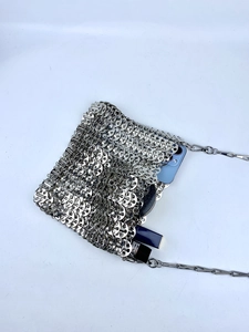 Interior view of silver metal scale bag holding a smartphone, compact and lipsticks