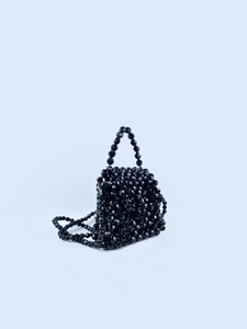 Detailed view of handmade black beaded crossbody bag with dual shoulder straps and handles