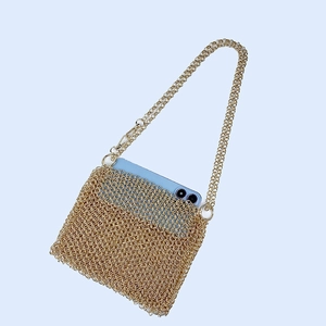 Detail of gold metal mesh bag showing woven texture and phone storage capacity