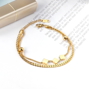 Close-up of gold double-layer stainless steel bracelet with clover charm and S.STEEL tag