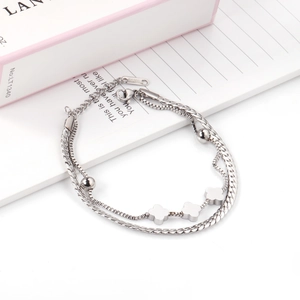 Detailed close-up of double-layer stainless steel bracelet with clover charms and S.STEEL stamp
