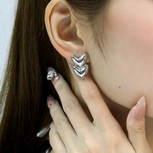 Macro detail of overlapping V-shaped silver earrings in polished 18K gold-plated steel