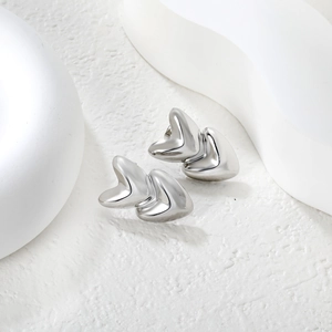 Macro detail of triple layered silver heart stud earrings with polished mirror finish