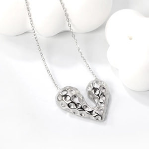 Close-up of silver heart pendant with hammered texture and delicate O-chain