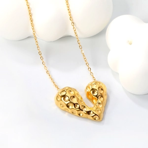 Detailed close-up of a 18K gold-plated heart pendant with unique hammered textured surface