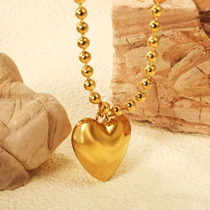 Detail of 18K gold plated heart pendant necklace with ball chain on natural stone