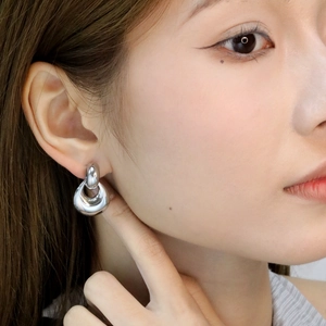 Macro shot of silver dual-hoop earrings featuring a high-polish finish on the earlobe