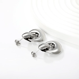 Detail of silver hollow teardrop earrings with high-polish finish on a white background