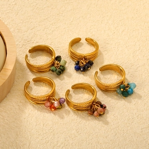 Detailed view of five adjustable gold-plated rings with colorful natural stone charms