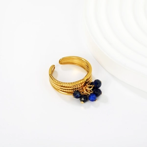 Detail of adjustable gold ring with blue bead tassel and textured metal surface