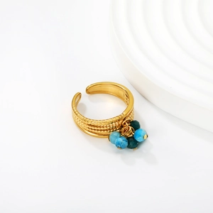 Close-up of golden adjustable ring with blue beaded tassels and textured surface