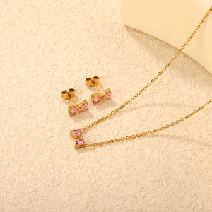 Conjunto de joyas en acero dorado con collar y pendientes de lazo y corazón rosa