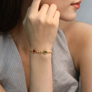 Bracelet élégant en perles dorées avec trois pendentifs en forme de cœur colorés