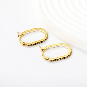 Detailed view of gold oval hoop earrings with shimmering crystal pavé on a white background
