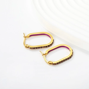 Macro view of oval gold-plated earrings with purple enamel and zircon inlay detail