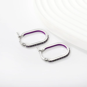 Detailed close-up of U-shaped silver earrings with purple enamel and crystal accents