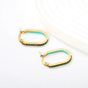 Macro detail of oval gold earrings with blue enamel inlay and crystal pavé setting
