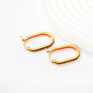 Detail of oval gold earrings with vibrant orange enamel and matching rhinestones