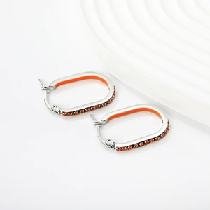 Close-up of silver oval hoop earrings with orange enamel and matching orange crystals