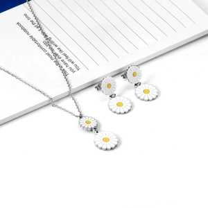 Detailed close-up of daisy jewelry set with white enamel petals on a notebook background