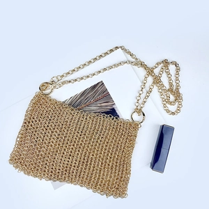 Macro detail of the golden metal sequin mesh texture and hand-woven chain strap