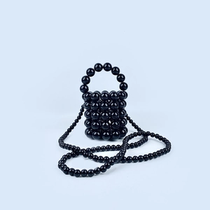 Detailed view of a mini black handmade beaded bucket bag with elegant pearl-like sheen