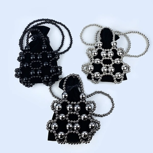 Detailed view of handmade beaded handbags in black, silver, and grey with velvet liners