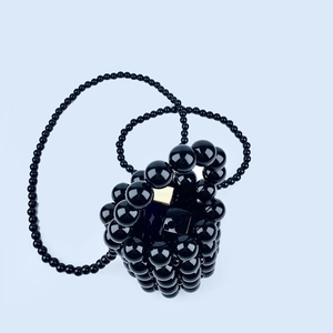 Detail of handmade black beaded mini bucket bag with glossy beads and gold metal buckle