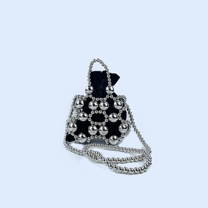 Macro view of metallic beaded handbag with silver spheres and a black velvet drawstring pouch