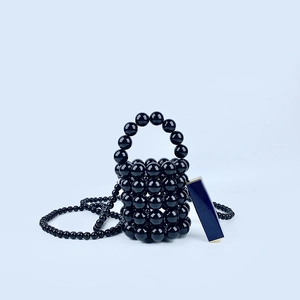 Detail of black handmade beaded mini bucket bag shown with lipstick for scale comparison