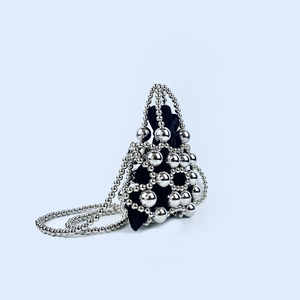 Detailed close-up of a silver beaded pyramid handbag with a black velvet interior pouch