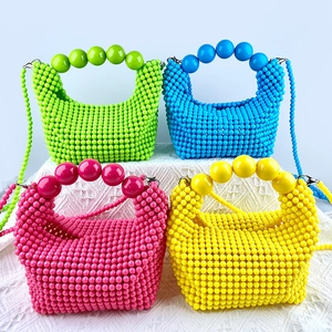 Detail of four colorful handmade beaded bags featuring large top handles and shoulder straps