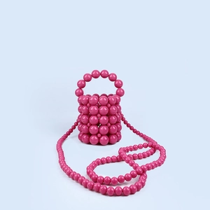 Detail of rose pink hand-woven beaded bucket bag with spherical resin pearls and shoulder strap