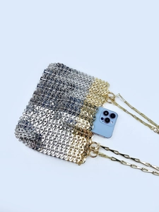 Detail showing internal capacity of gold and silver metal mesh bag with a smartphone