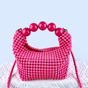 Detail of pink beaded handbag with large orb handle on white textured knit fabric