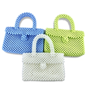 Detailed stack of handmade beaded handbags in sky blue, lime green, and pearl white colors