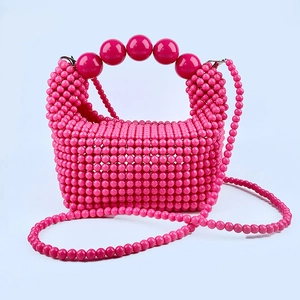 Detail of rose red handmade beaded handbag with large bead handle and long strap