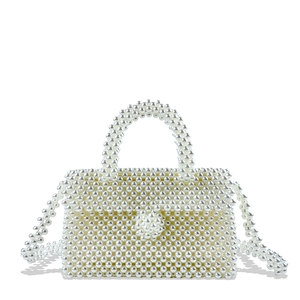 Macro detail of hand-woven white pearl handbag showing beaded texture and round clasp