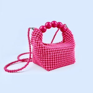 Close-up of rose red beaded handbag with large bead handle and removable shoulder strap