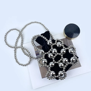 Detailed shot of silver beaded handbag with metallic spheres and black velvet drawstring liner